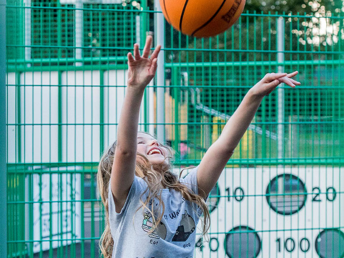 Young girl playing basketball on a multi sports court